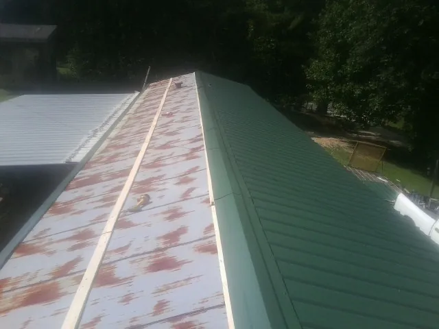 Old rusted panels beside newly installed green metal roofing — Wind Damage Roof Repair by Roofing Brothers in Falmouth